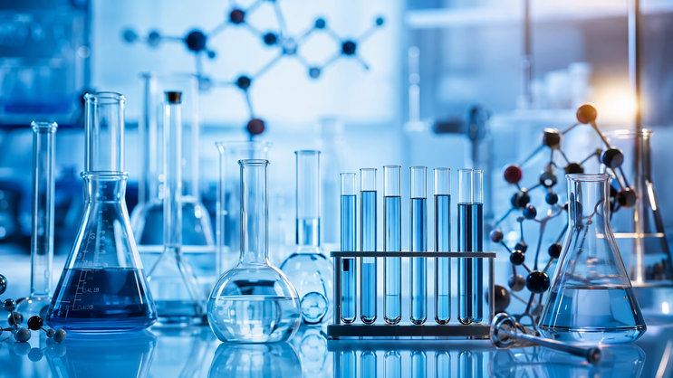 AI-generated illustration of a chemistry flask, test tubes in a rack, and a molecular model kit, representing the lab's work in heterocyclic chemistry.

